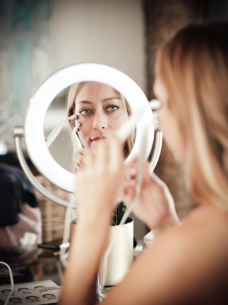 Woman performs skincare routine with beauty device in front of mirror.