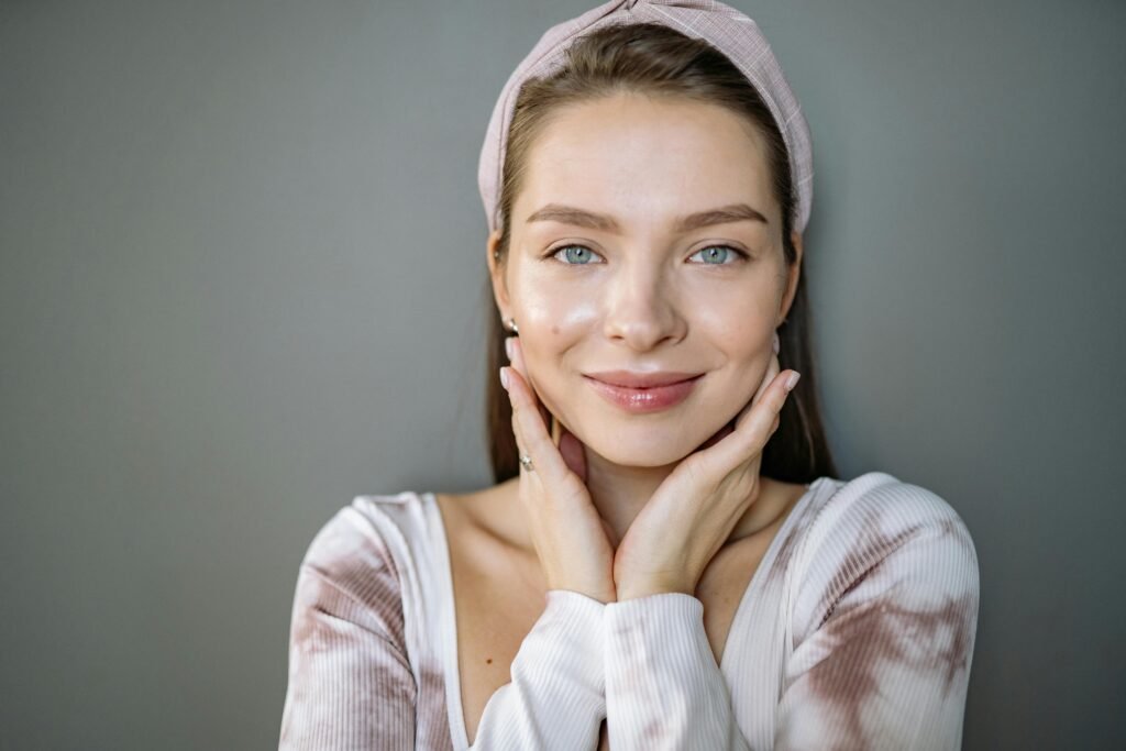 Portrait of a smiling woman with healthy skin wearing a headband on a gray background.