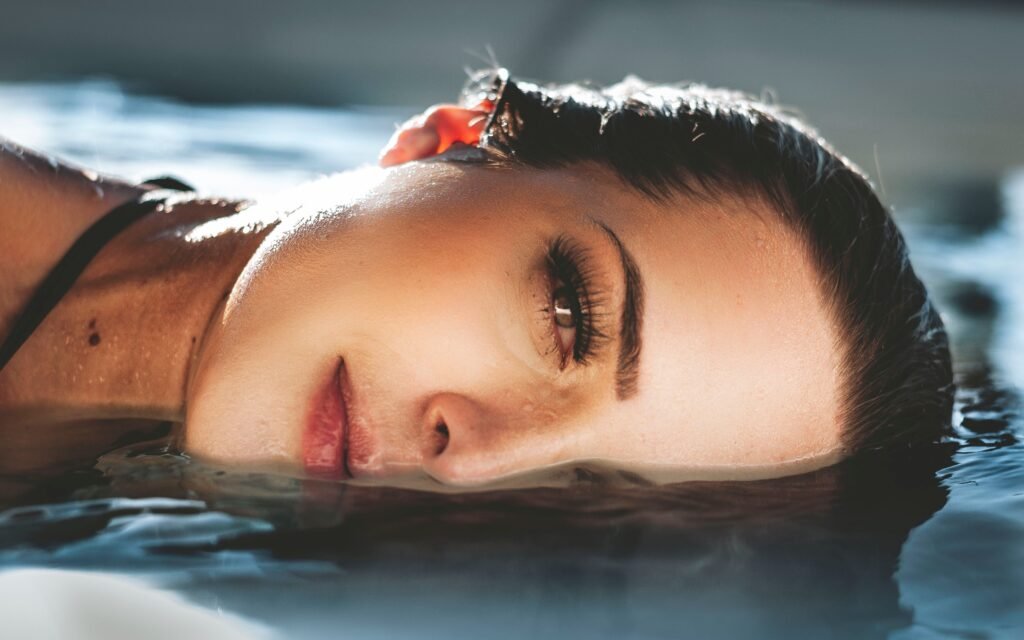 Close-up of a serene woman's face half-submerged in water, capturing tranquility and reflection.