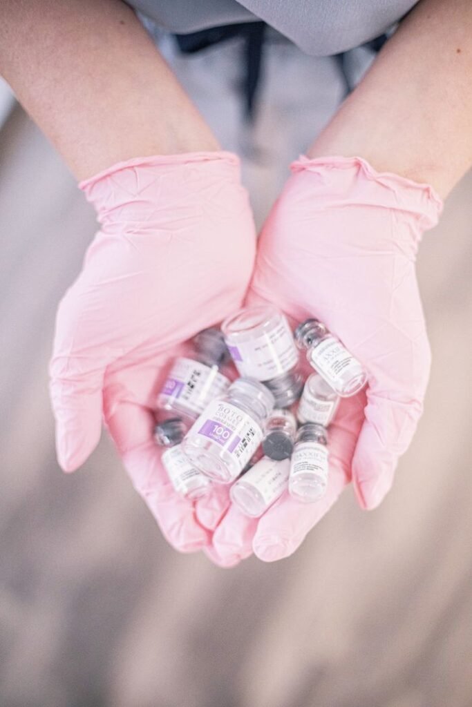 Close-up of pink gloved hands holding cosmetic treatment vials, symbolizing modern skincare.